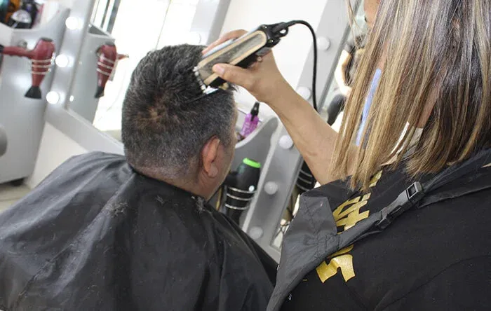 Barbero realizando un corte de cabello masculino con maquina